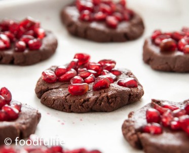 raw cocoa cookies and garnished with pomegranate seeds on backing paper, on an oven trey